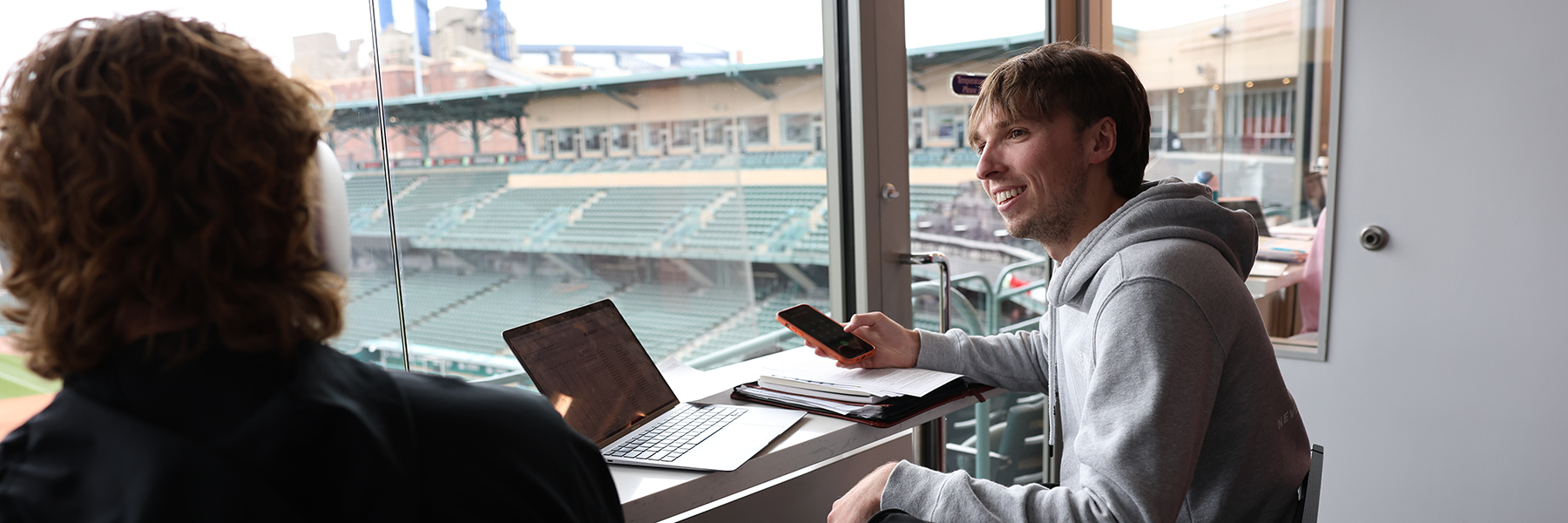 Student smiling in suite at baseball field 