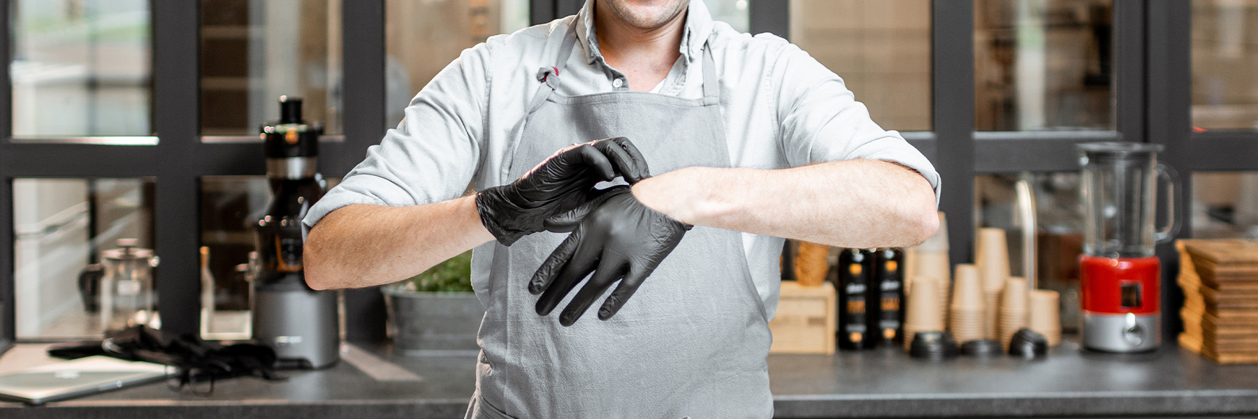 A male standing in a kitchen wearing black gloves