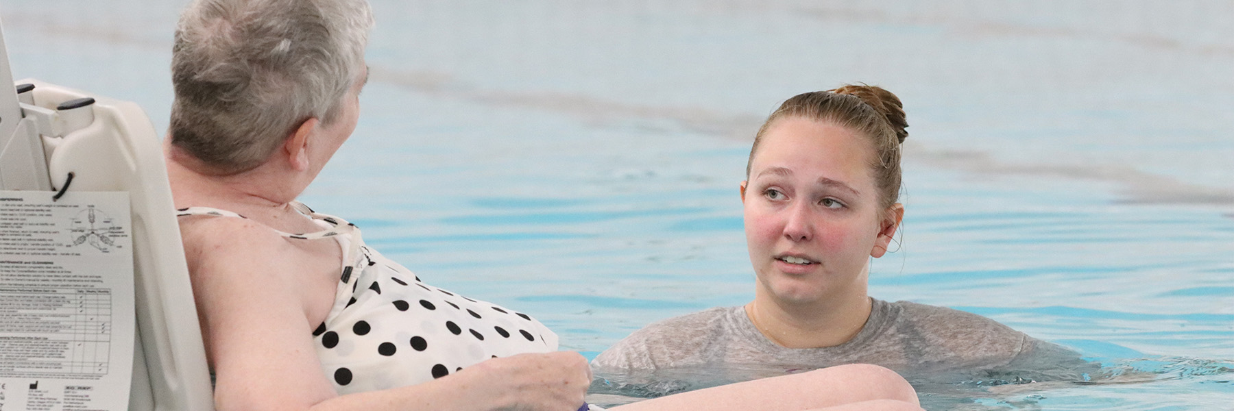 A student working with an older patient during a swim class