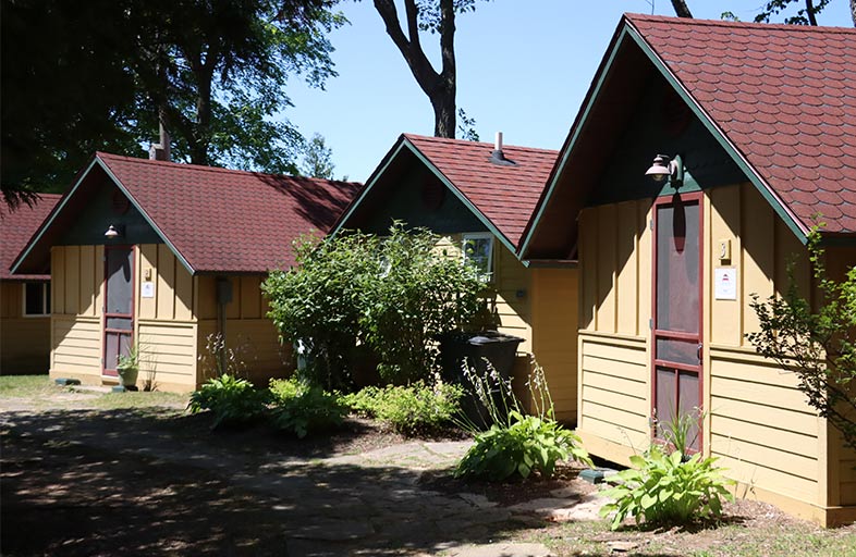 A row of small yellow and brown camp houses amid trees