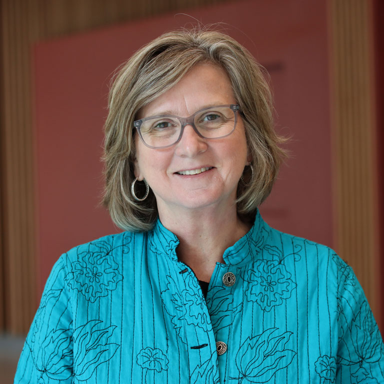 Julie Bednarski smiling in a room with a red background