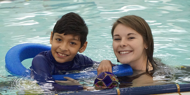 A student with a community member in the pool